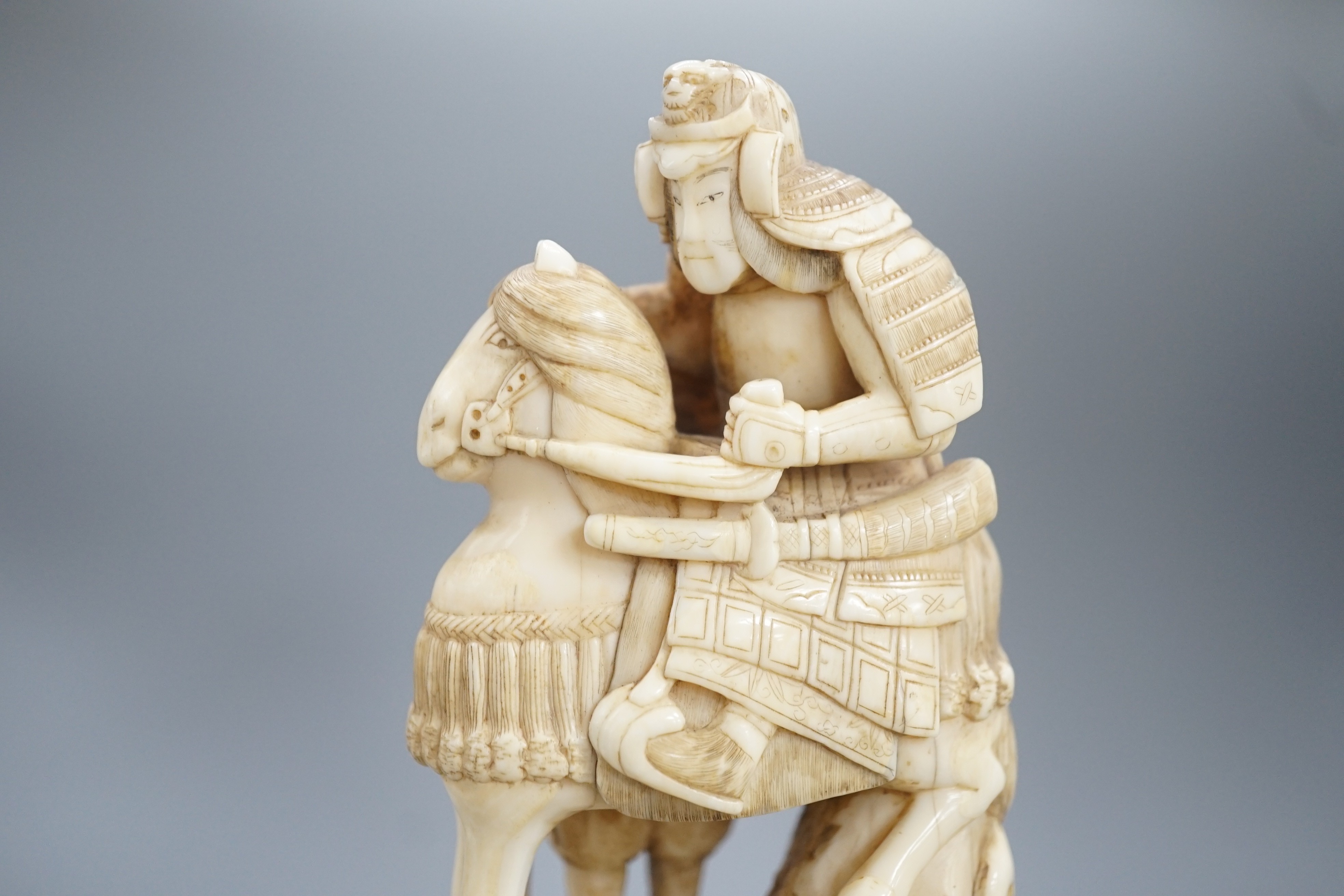 A Japanese ivory okimono of a samurai on horseback, with an attendant behind him, signed, late 19th century 12cm